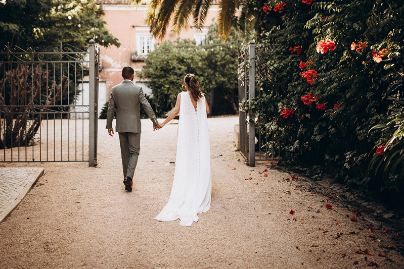 Bride and groom walking through the gates of a historic estate during a wedding in Portugal.