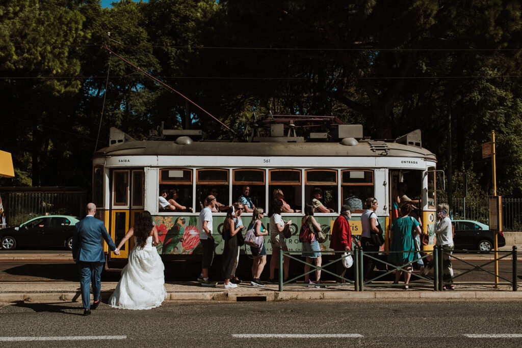 Bride and groom walking near a Lisbon tram during a small wedding in Lisbon, Portugal.