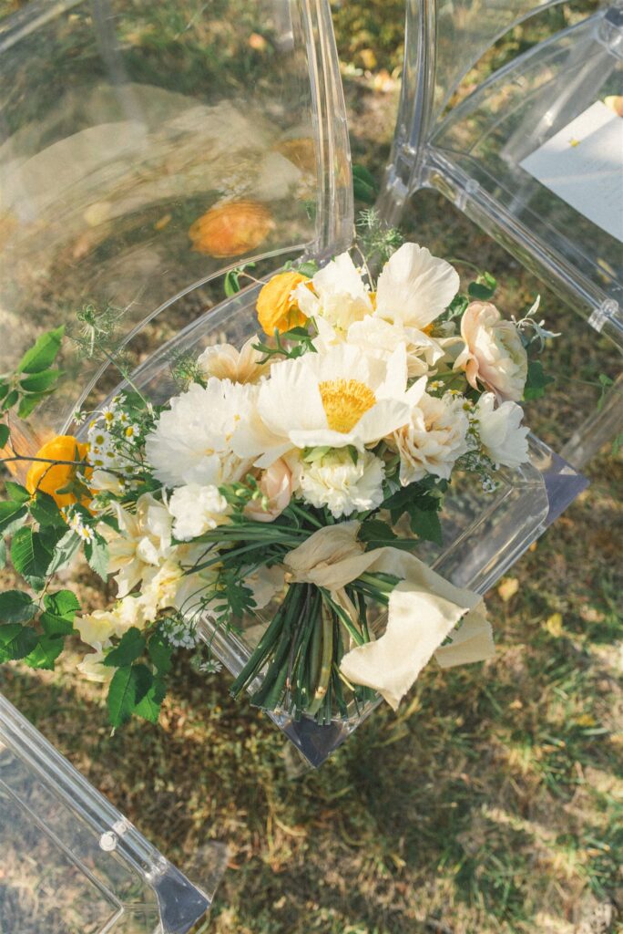 Wedding bouquet with soft floral arrangement on transparent chair during outdoor ceremony in Alentejo Portugal